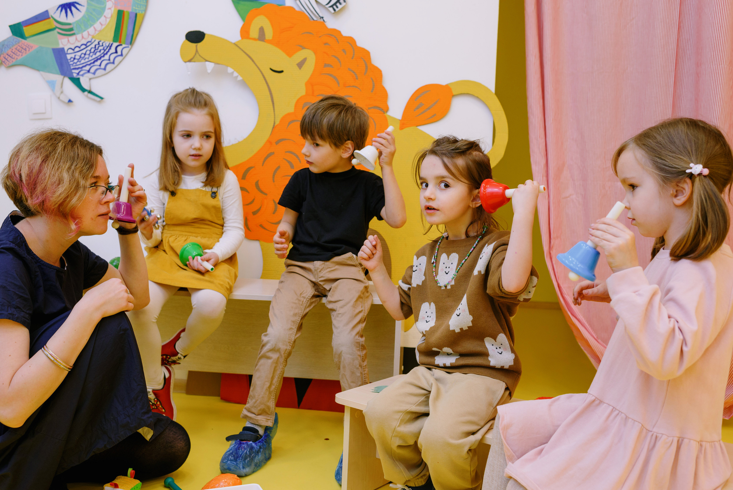 Children with Her Students Holding Different Color Bells